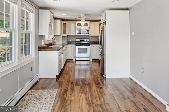 kitchen with stainless steel appliances, ceiling fan, baseboard heating, sink, and dark hardwood / wood-style floors