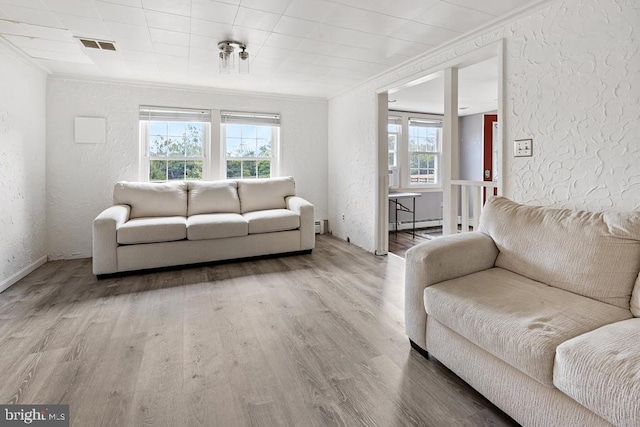 living room featuring wood-type flooring, ornamental molding, a wealth of natural light, and a baseboard radiator