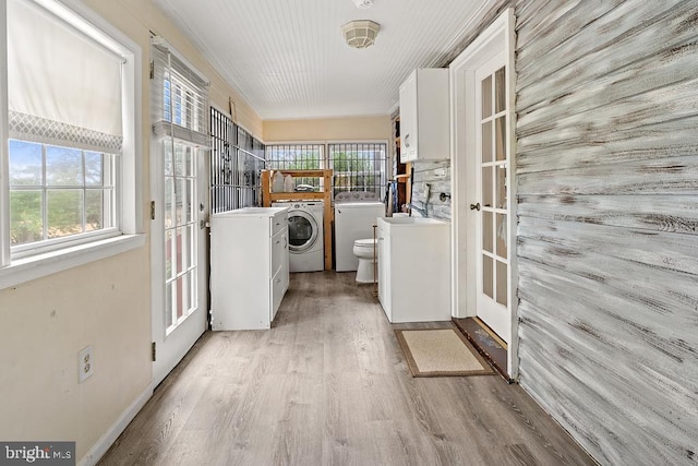 washroom with washing machine and dryer, light hardwood / wood-style floors, and a healthy amount of sunlight