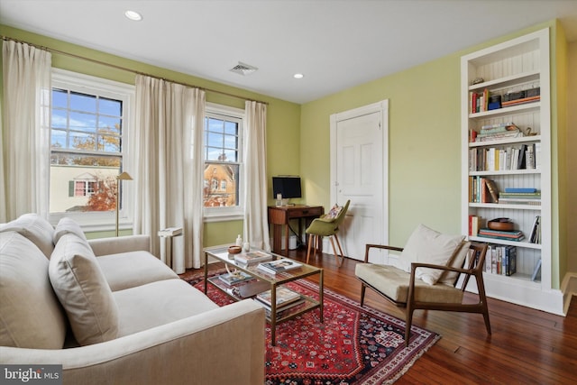 sitting room featuring built in shelves and dark wood-type flooring