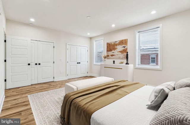 bedroom with multiple windows, multiple closets, and light hardwood / wood-style floors