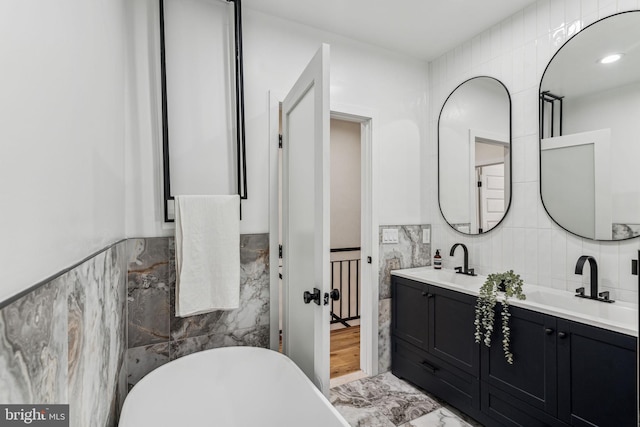 bathroom with vanity, tile walls, and a bathing tub