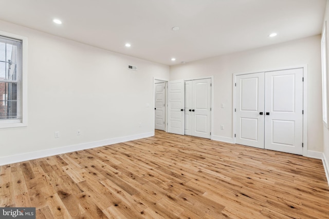 unfurnished bedroom featuring light hardwood / wood-style flooring and two closets