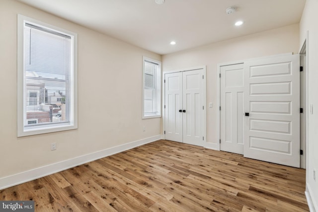 unfurnished bedroom with multiple windows, multiple closets, and hardwood / wood-style flooring