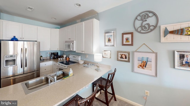 kitchen featuring white appliances, white cabinets, sink, kitchen peninsula, and a breakfast bar