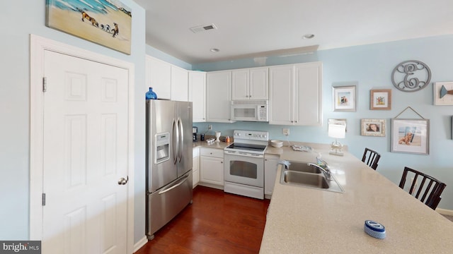 kitchen with dark wood-type flooring, sink, white appliances, and white cabinetry