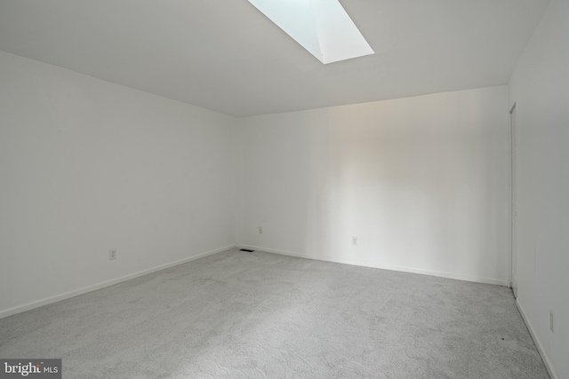 empty room with a skylight and light colored carpet