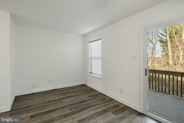 spare room featuring dark wood-type flooring and a healthy amount of sunlight