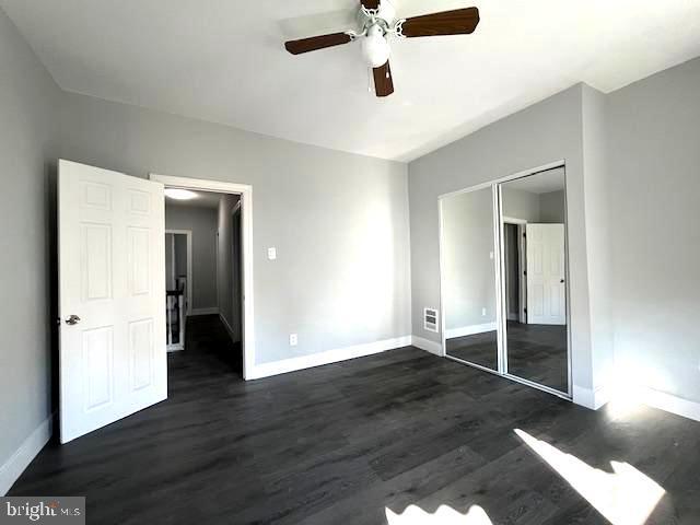 unfurnished bedroom with ceiling fan, dark hardwood / wood-style flooring, and a closet