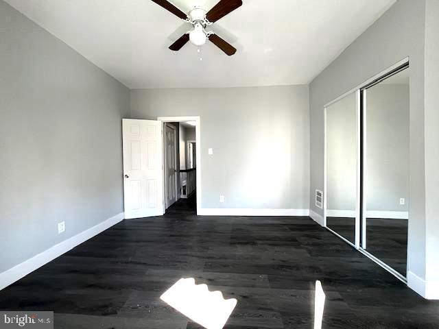 unfurnished bedroom with a closet, ceiling fan, and dark hardwood / wood-style flooring