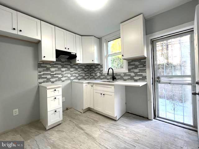 kitchen with decorative backsplash, sink, and white cabinets