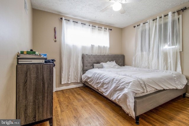 bedroom featuring ceiling fan, wood-type flooring, and a textured ceiling