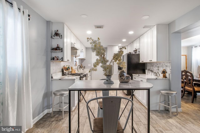 kitchen with kitchen peninsula, white cabinets, and light hardwood / wood-style floors