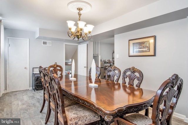 dining space with light hardwood / wood-style flooring and a notable chandelier