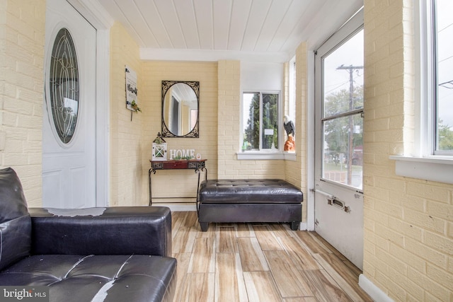 living area featuring brick wall and light wood-type flooring