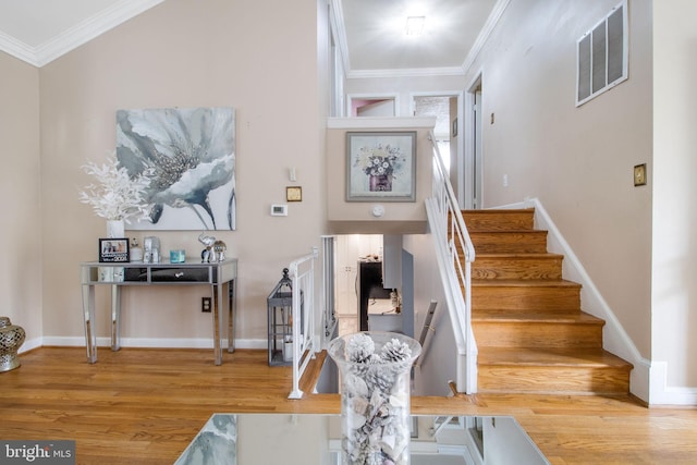 stairway featuring ornamental molding, lofted ceiling, and hardwood / wood-style flooring