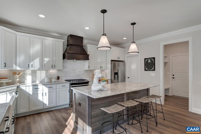 kitchen featuring appliances with stainless steel finishes, premium range hood, a kitchen island, and white cabinetry