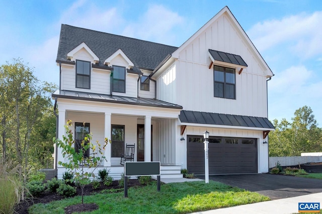 modern farmhouse with a porch, a garage, and a front lawn