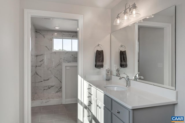 bathroom featuring tile patterned flooring, vanity, and tiled shower