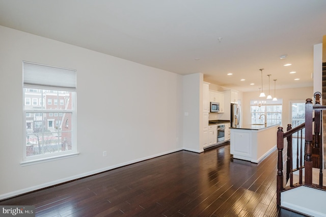 living area featuring a chandelier, baseboards, dark wood finished floors, and recessed lighting