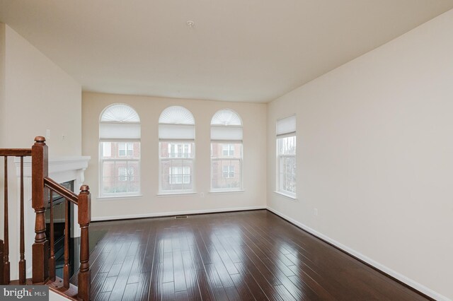 unfurnished living room featuring baseboards and dark wood-type flooring