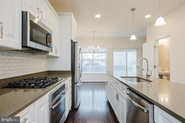 kitchen with dark wood-style flooring, a sink, white cabinetry, appliances with stainless steel finishes, and backsplash