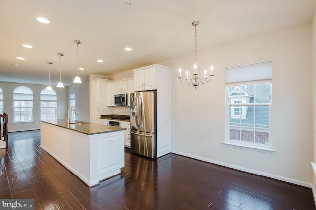 kitchen with appliances with stainless steel finishes, dark countertops, dark wood-style flooring, and a sink