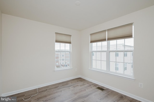 empty room with visible vents, baseboards, and wood finished floors