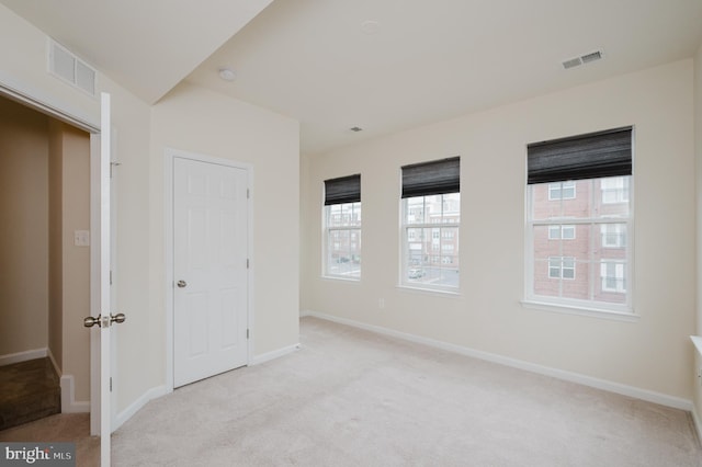 unfurnished bedroom featuring visible vents, light carpet, and baseboards