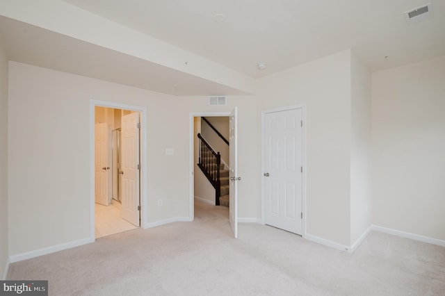 unfurnished bedroom with baseboards, visible vents, and light colored carpet