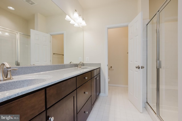 bathroom featuring toilet, a stall shower, visible vents, and a sink