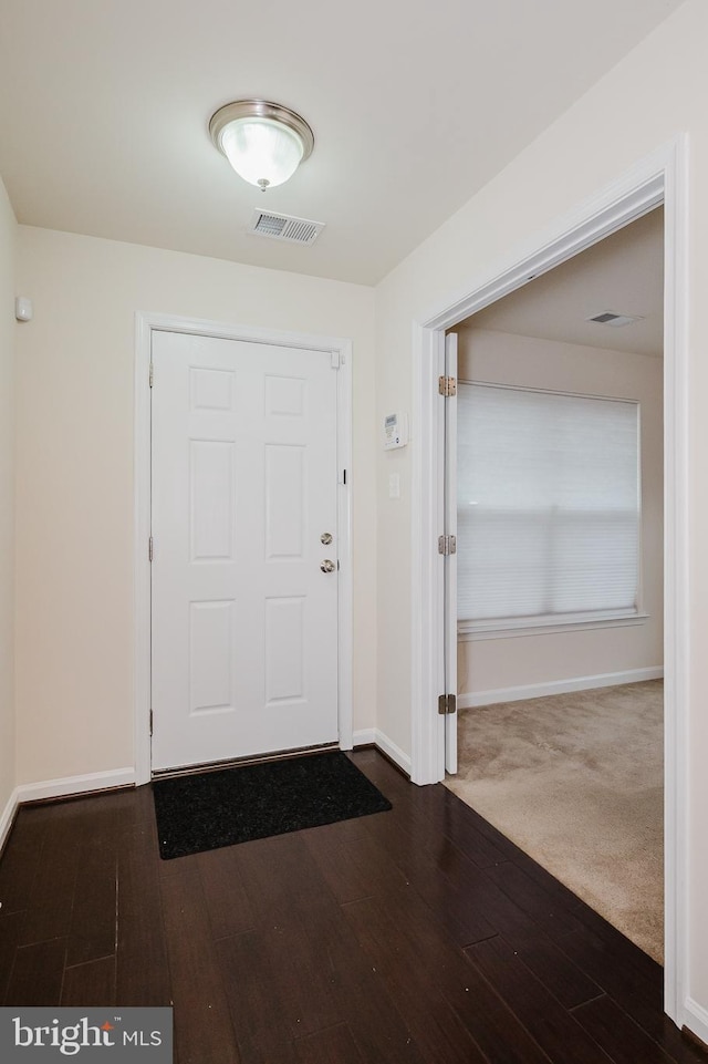 foyer entrance with dark wood-style flooring, visible vents, and baseboards