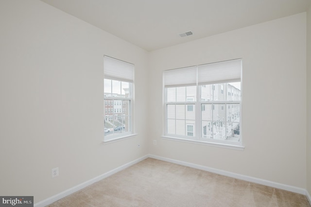 spare room featuring light carpet, baseboards, and visible vents