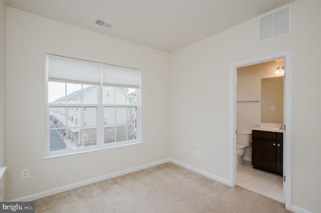 unfurnished bedroom with light carpet, baseboards, visible vents, and a sink