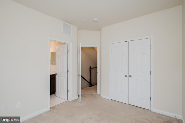 unfurnished bedroom with light colored carpet, a closet, visible vents, and baseboards