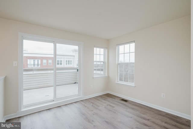 spare room with baseboards, visible vents, and wood finished floors