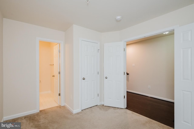 unfurnished bedroom with ensuite bath, baseboards, and carpet flooring