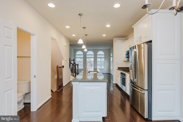 kitchen featuring recessed lighting, a sink, white cabinetry, appliances with stainless steel finishes, and an island with sink