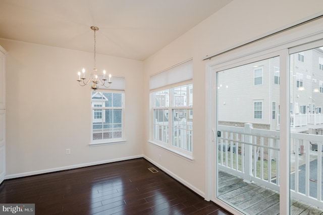 unfurnished dining area with baseboards, dark wood finished floors, and a chandelier