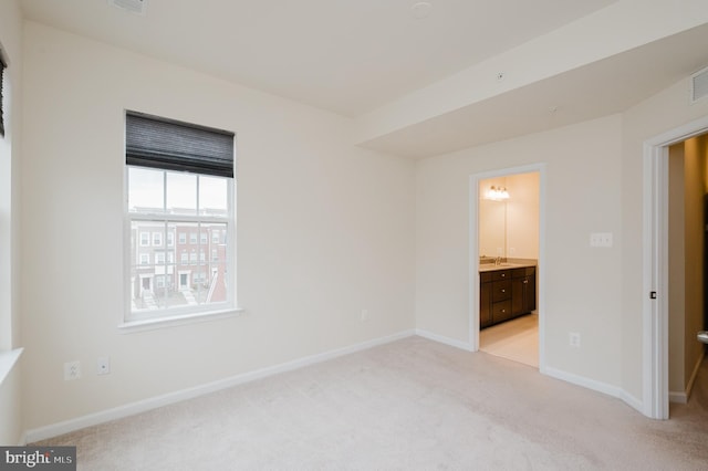 unfurnished bedroom with light colored carpet, visible vents, baseboards, and ensuite bathroom