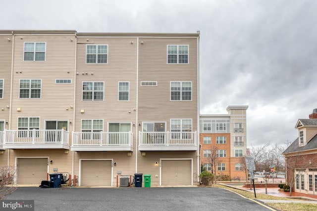 view of building exterior featuring a garage, central AC, and driveway