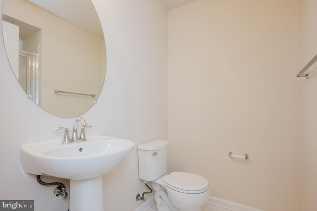 bathroom with a sink, toilet, and baseboards