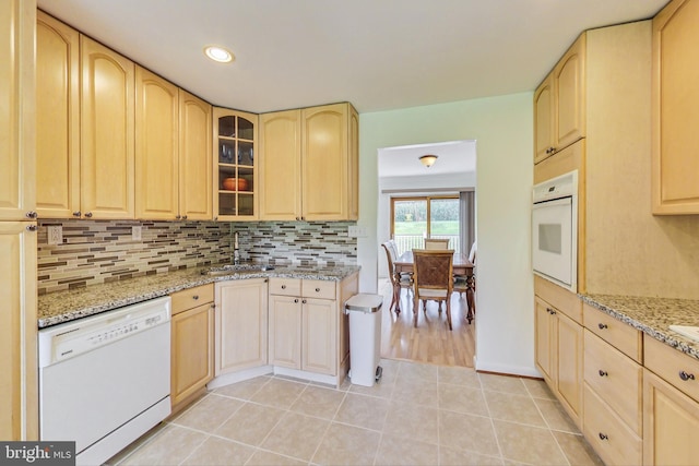 kitchen featuring light stone countertops, white appliances, sink, and light brown cabinetry