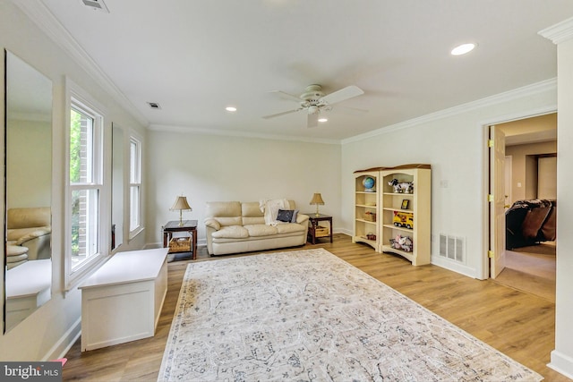 living room with light wood-type flooring, ornamental molding, and a wealth of natural light