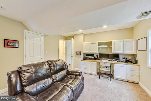 living room featuring light colored carpet, built in desk, and vaulted ceiling