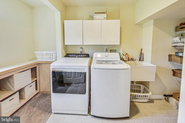 clothes washing area with washer and clothes dryer, cabinets, light tile patterned floors, and sink