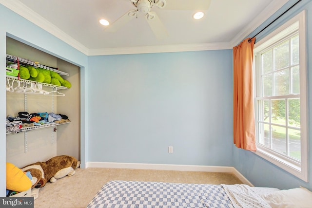 carpeted bedroom with a closet, ceiling fan, and crown molding