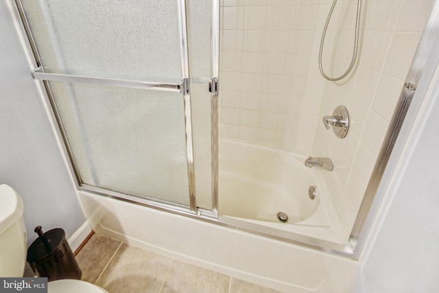 bathroom featuring combined bath / shower with glass door, tile patterned flooring, and toilet