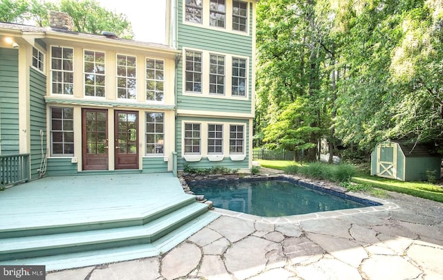 view of pool with a storage shed and a deck