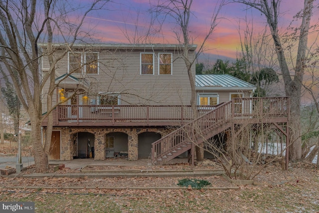 back house at dusk with a wooden deck and a patio area